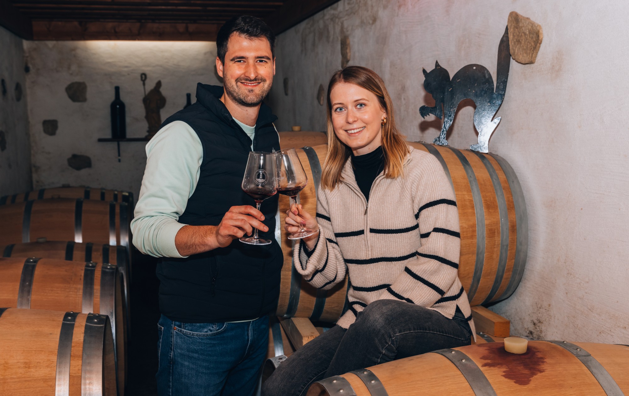 Michael Dombi und Anna stoßen im Barriquekeller mit Rotwein an