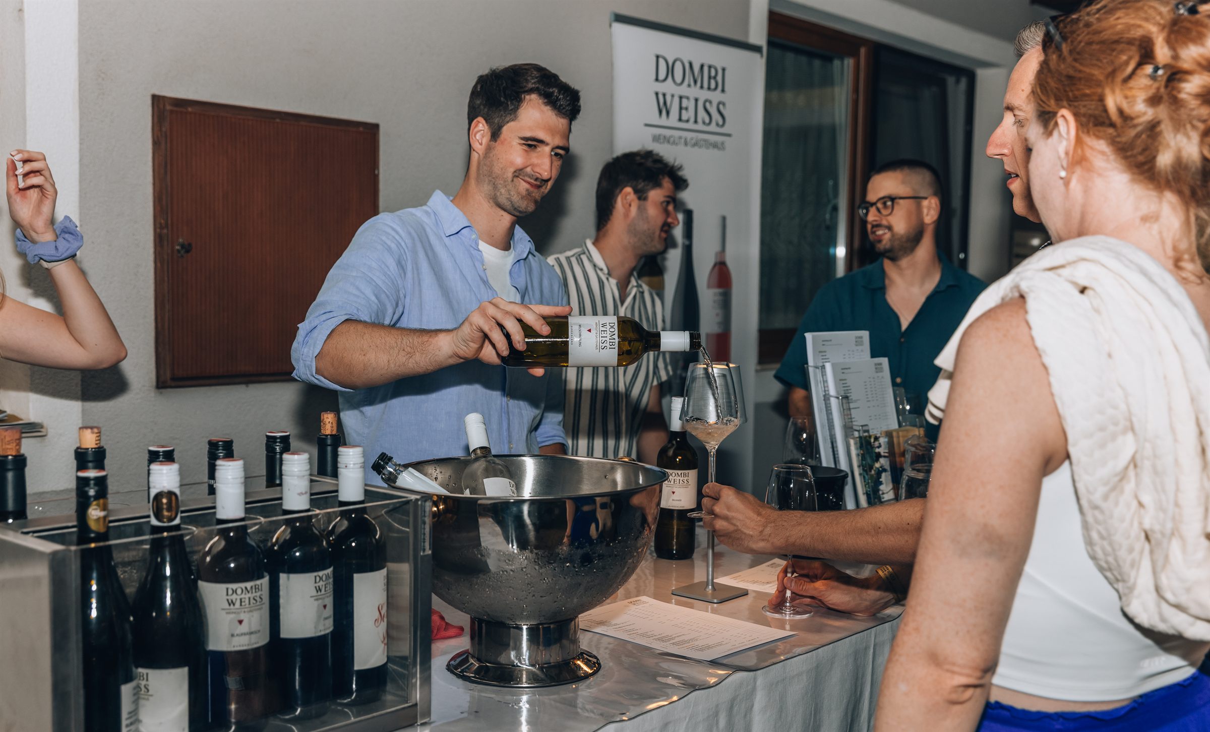 Michael schenkt bei Wein³ Weißwein aus, dahinter Andreas und Daniel